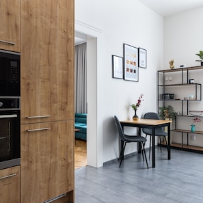 Une cuisine moderne avec des meubles en bois, un coin repas avec une table et des chaises, et un salon avec un canapé.