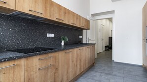 A modern kitchen with wooden cabinets, a granite countertop, and a built-in stove. - City Buzz Apartment - O2 Arena - Sleeps 6 (Prague)