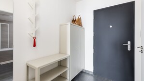 A hallway with a white bench, a white cabinet, and a black door.