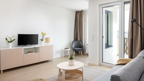 A modern living room with a flat-screen TV, a sofa, a coffee table, and a chair.