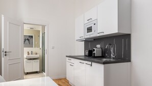 Een moderne keuken met witte kasten, een zwart aanrecht en een magnetron.