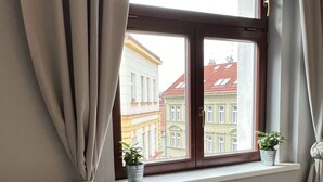 Ein Zimmer mit Fenster, einer Couch und zwei Blumentöpfen auf der Fensterbank.