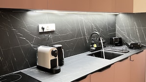 Une cuisine moderne avec un dosseret en marbre noir, un four encastré, une machine à café et un évier.