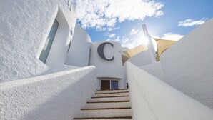 A white-walled building with a staircase leading to a door marked with a large 'C'.