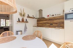 A modern kitchen with white cabinets, a wooden countertop, and a built-in oven. - Luxe holidayhome - Brouwersbuurt 23a | Domburg (Domburg)
