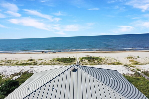 A beach view from a building with a sloped roof, sandy beach, and ocean. - White Pelican (Port St. Joe)
