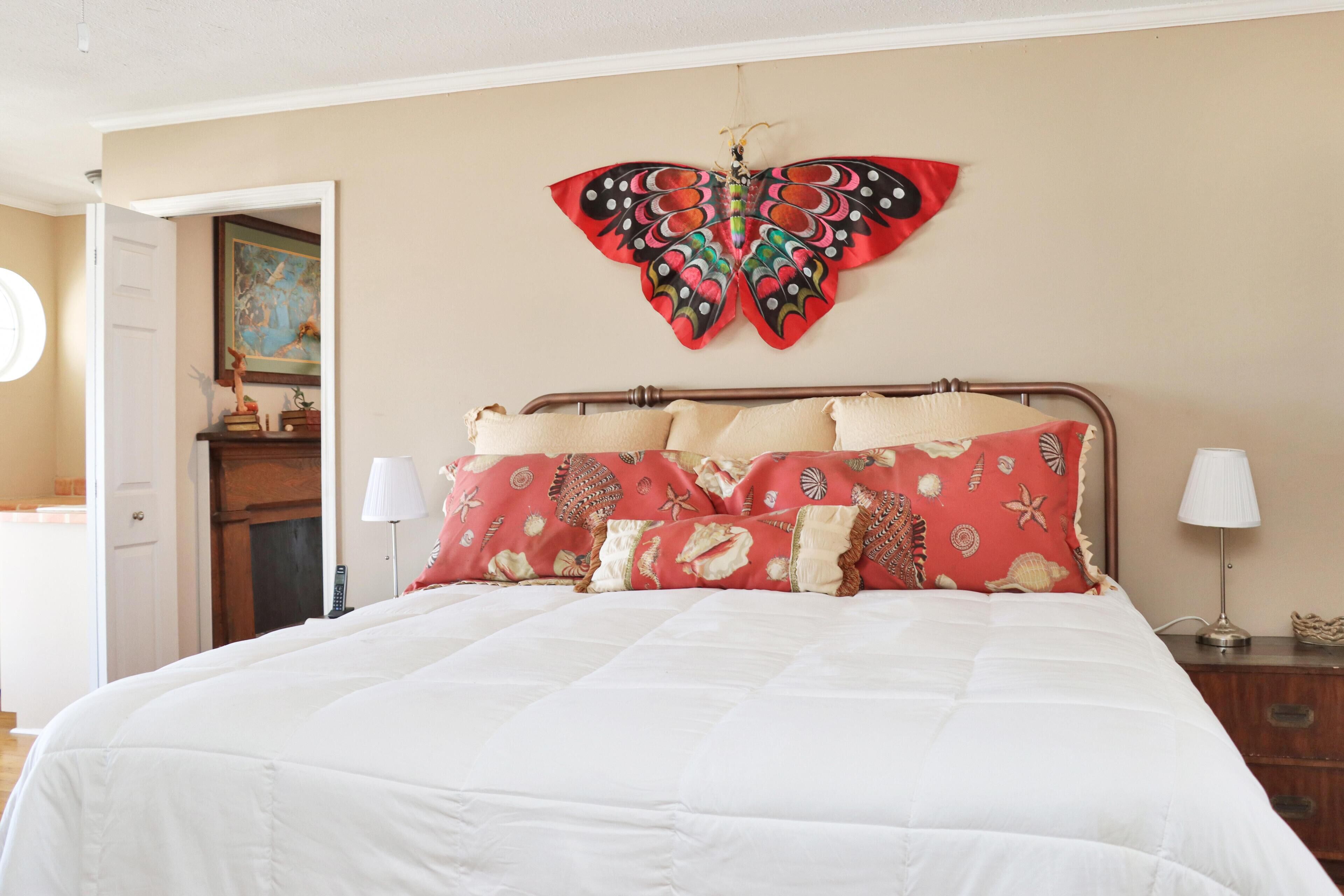 Una camera da letto con un letto, una decorazione a farfalla al muro e una porta che conduce in un'altra stanza.