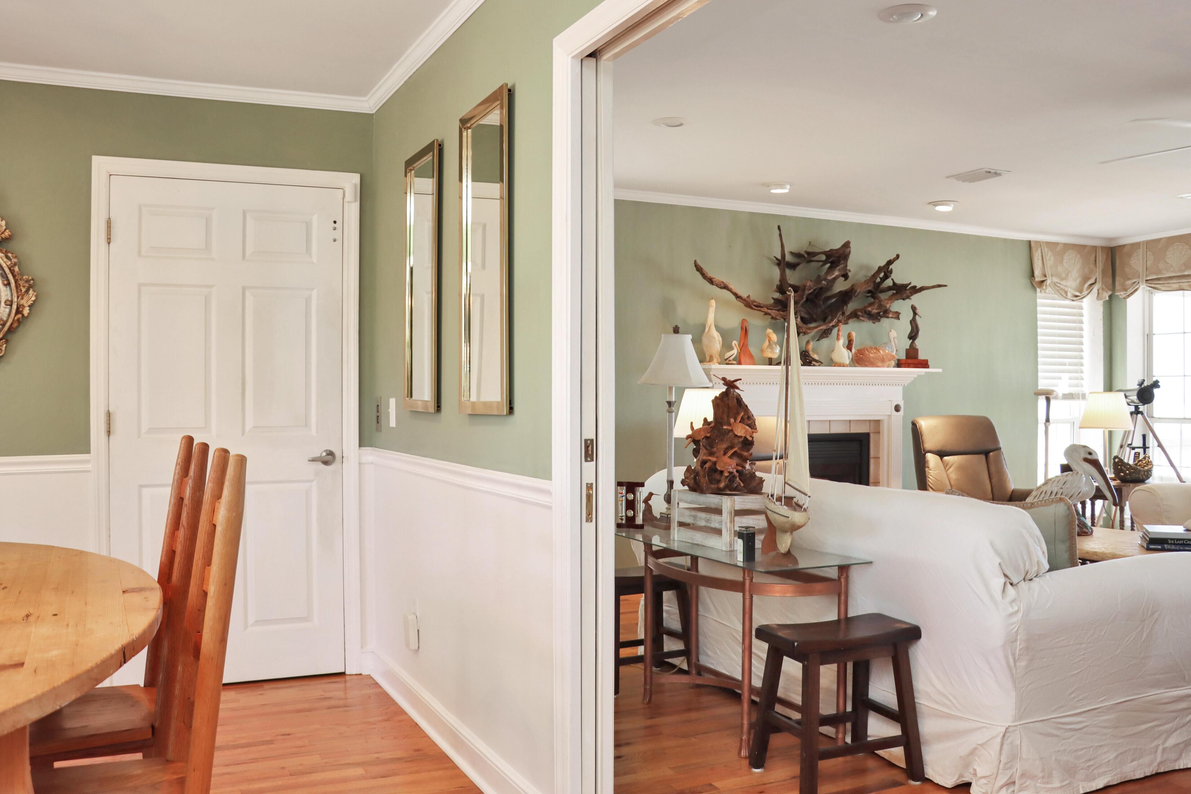 A room with a dining table, chairs, a bed, a fireplace, and a mirror.