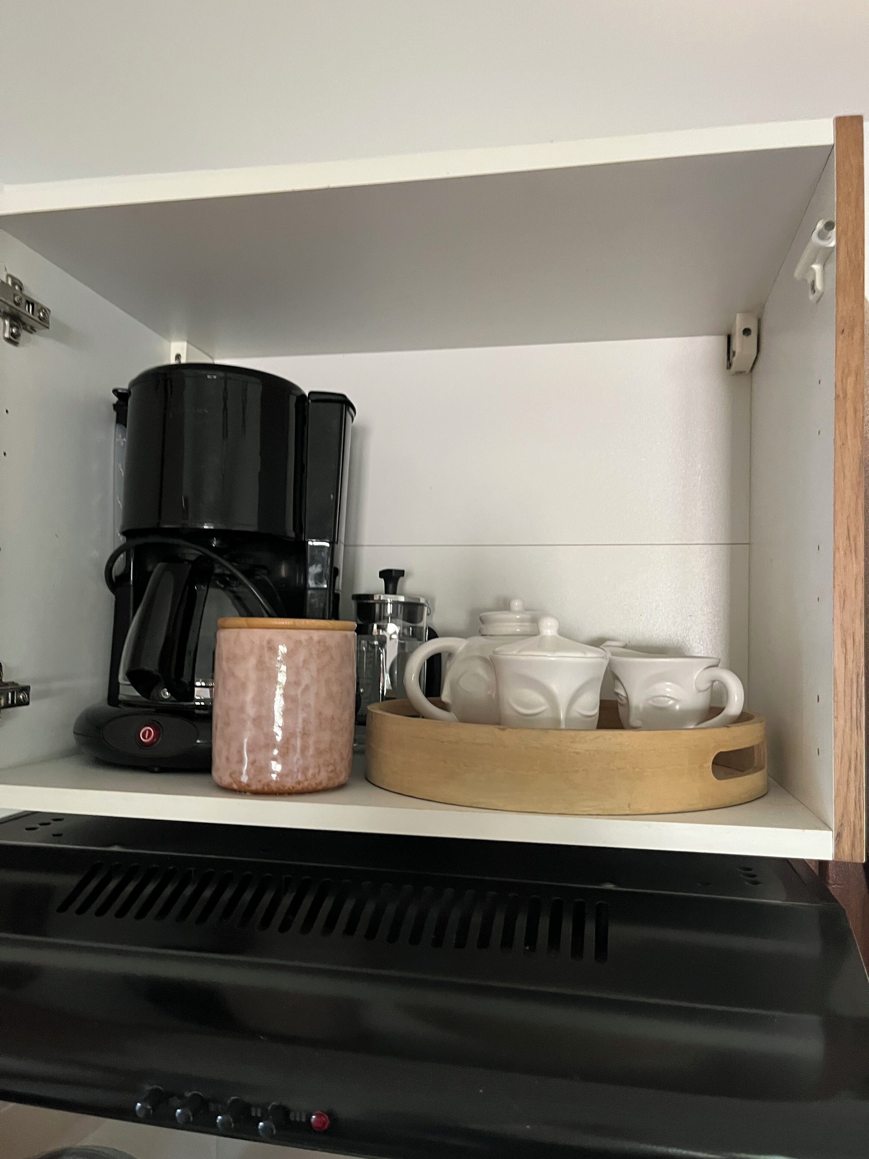 Una cocina con cafetera, una taza y una bandeja con tazas.