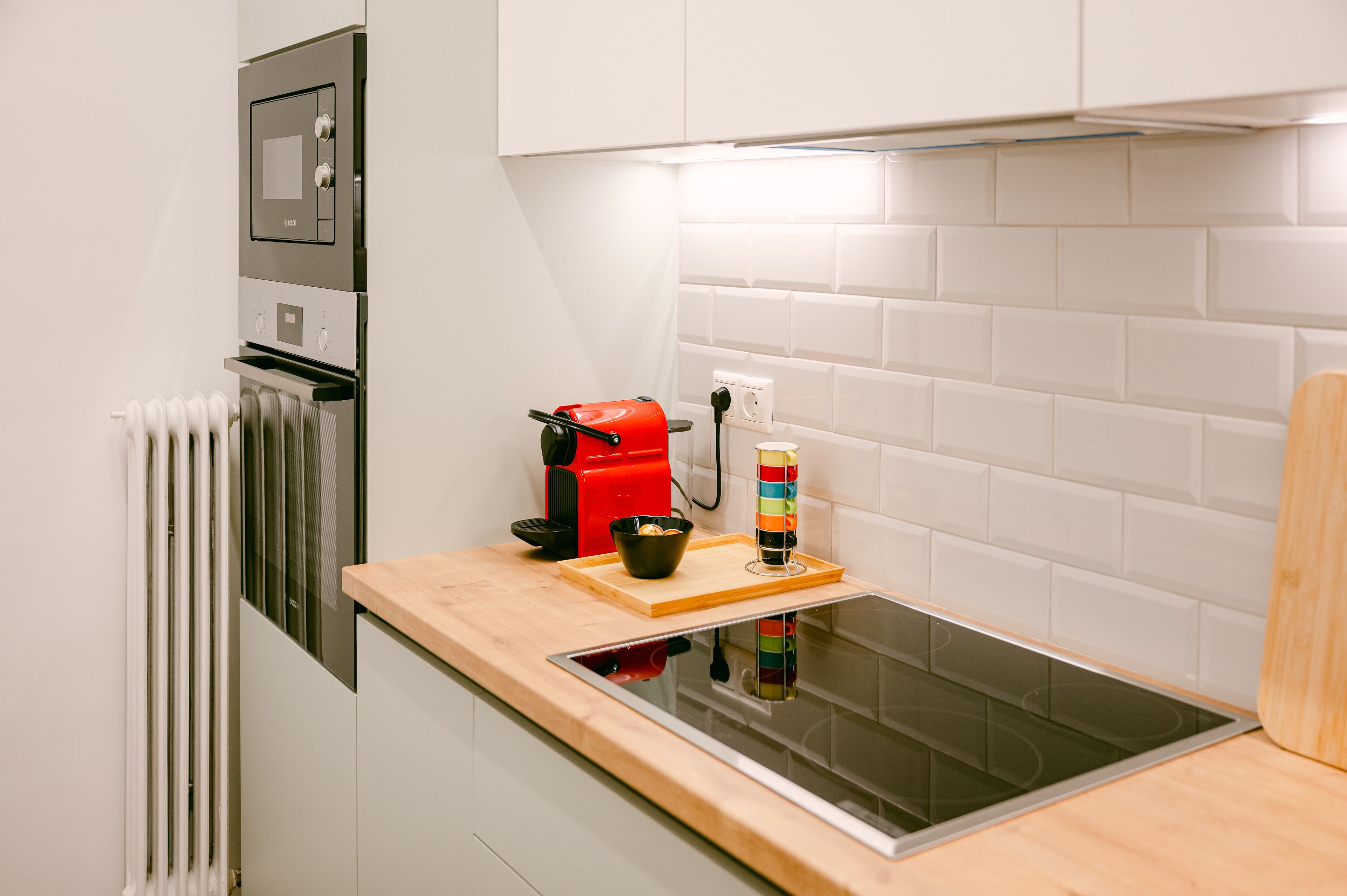 A modern kitchen with a built-in oven, a coffee maker, and a colorful striped container on the counter.