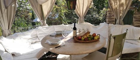 A round table set for two with a bottle of wine, a fruit basket, and a candle.