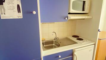 A compact kitchenette with a microwave, sink, and a small refrigerator.