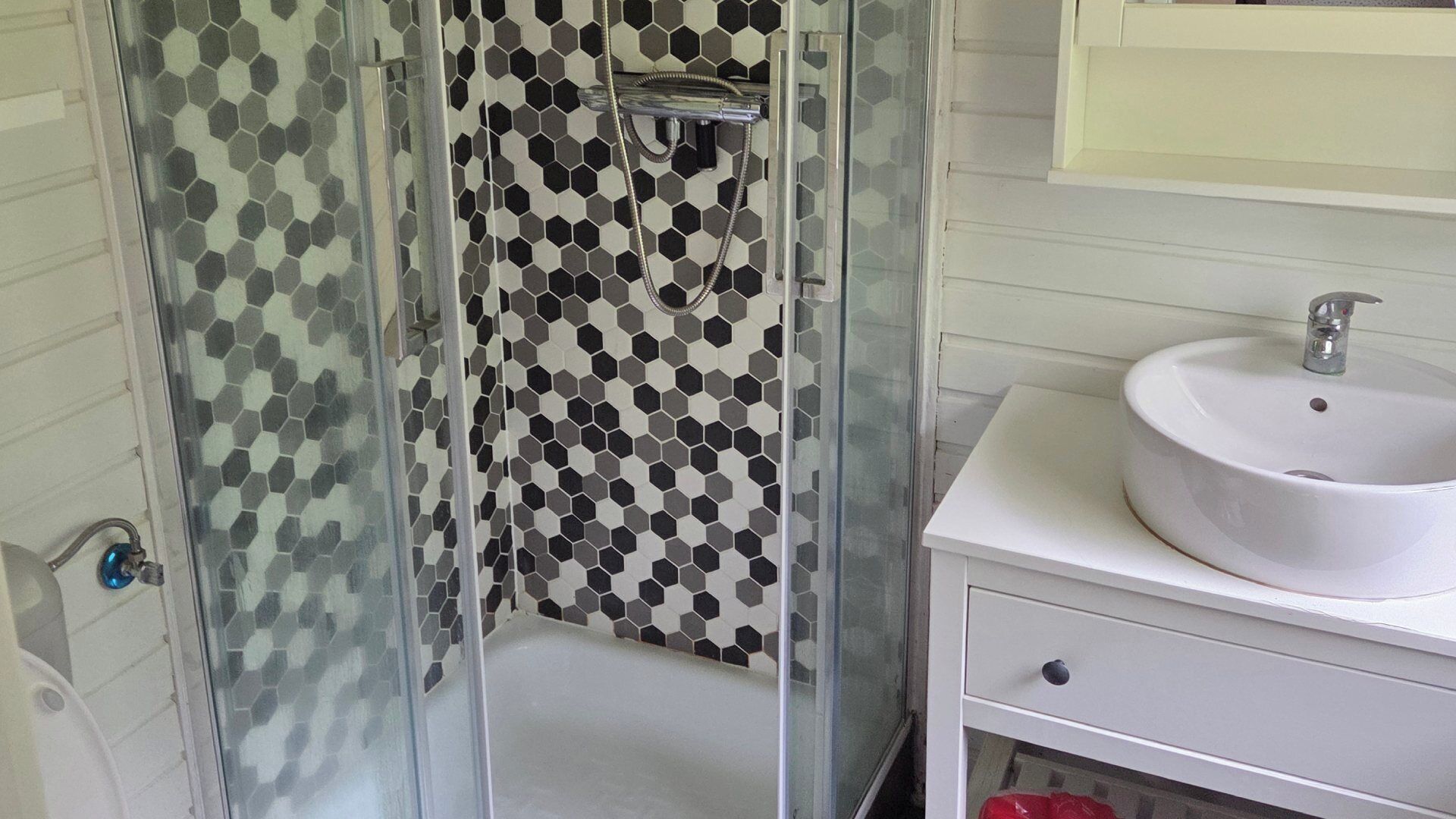 Une salle de bain avec une douche à parois de verre, un lavabo blanc et un miroir au-dessus du lavabo.