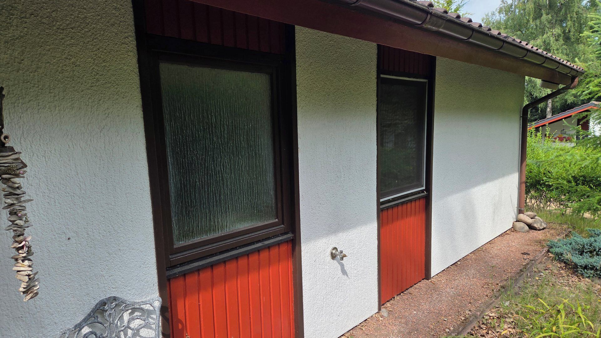A house with a white exterior, two red doors, and a window with a textured glass pane.