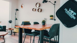 Un comedor moderno con una mesa de madera y sillas negras, un radiador y espejos en la pared.