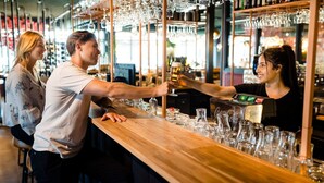 Eine Bar mit einem Holzbalken, Gläsern und einem Coca-Cola-Kühlschrank.