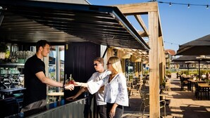 Ein Außenbereich mit Bar, Sitzgelegenheiten und einer überdachten Terrasse.