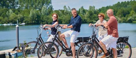 Cuatro personas paseando en bicicleta sobre un muelle junto a un lago.