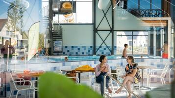 An indoor swimming pool area with a view of a residential neighborhood.
