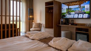 A hotel room with a bed, a chair, a TV displaying a scenic landscape, and a small table with a lamp. - Lake View Penthouse 4p (Thorn)