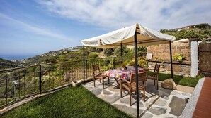 A patio with a table and chairs, a white canopy, and a stone wall. - Studio Timo - Studio Apartment, Sleeps 3 (Pompeiana)
