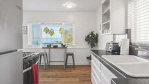 A modern kitchen with a view of the ocean, a stove, a sink, and a dining area with a window. - Huge Outdoor Space/Steps to Beach & Wedding Bowl (La Jolla)