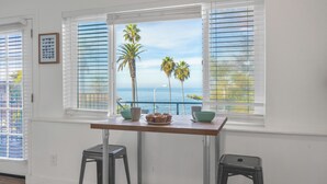 A kitchen with a view of the ocean, a table with bowls and a muffin tray, and two stools. - Huge Outdoor Space/Steps to Beach & Wedding Bowl (La Jolla)