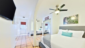 A hotel room with a bed, a ceiling fan, a TV, and a view of the hallway. - Huge Outdoor Space/Steps to Beach & Wedding Bowl (La Jolla)