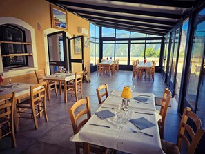 Un restaurante con varias mesas y sillas, amplias ventanas que ofrecen vistas a las montañas.