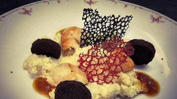 A plate with various food items including a piece of salmon, a dark round item, and a decorative element.