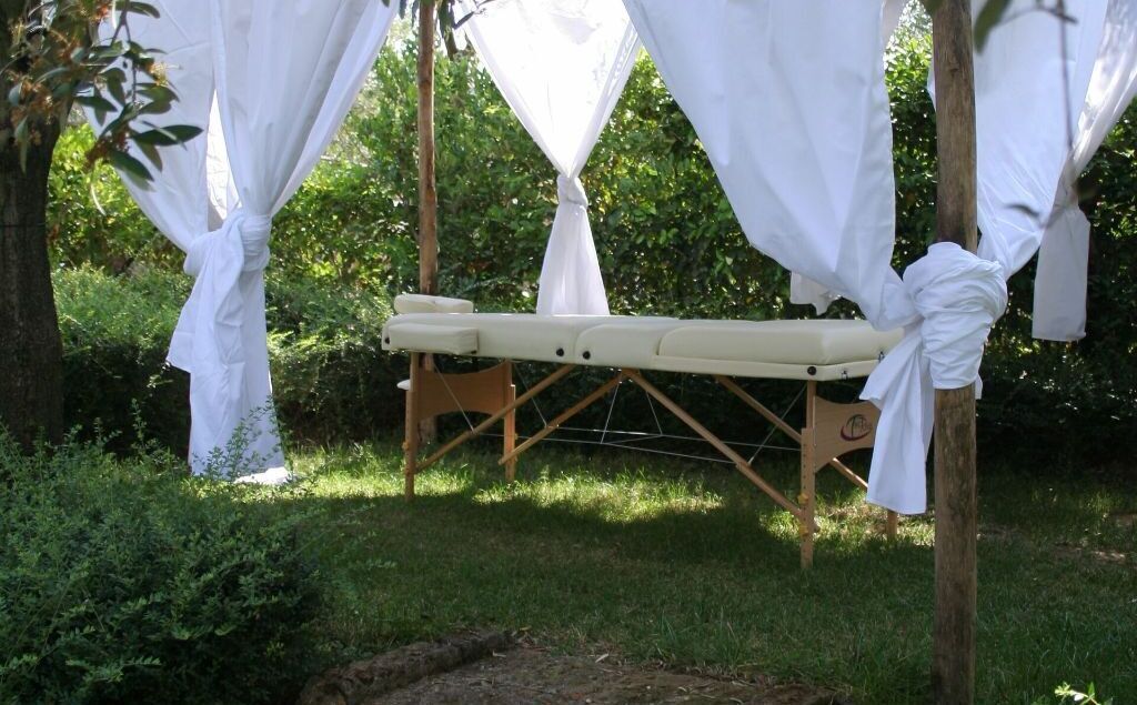 Ein hölzerner Massagetisch mit weißem Baldachin in einem Garten.
