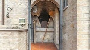 A narrow stone corridor with a tiled floor, a brick oven, and a wooden paddle.