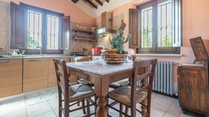 A kitchen with wooden cabinets, a marble countertop, and a dining table with chairs.