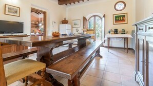 A kitchen with wooden benches, a television, and a refrigerator.