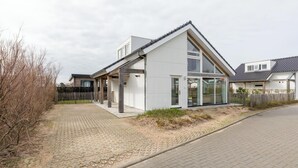 Una moderna casa a un piano con tetto inclinato, ampie finestre e una veranda coperta.