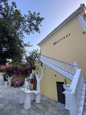 A building with a beige exterior and a staircase with white balustrades. - Marinos Rooms (Zakynthos)