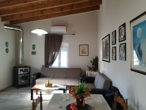 A living room with a sofa, a dining table with a vase, and framed pictures on the wall. - Villa Asterousia, Heraklion (Gortyna)