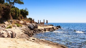 A rocky beach with a row of sun loungers and a clear view of the sea.