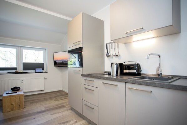 A modern kitchen with a built-in oven, a sink, and a window with a view of the outdoors.