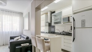 A modern kitchen with white cabinets, a built-in microwave, and a stainless steel refrigerator. - WI-FI 100MB | 200m from Beiramar Shopping #CA44D (Florianópolis)
