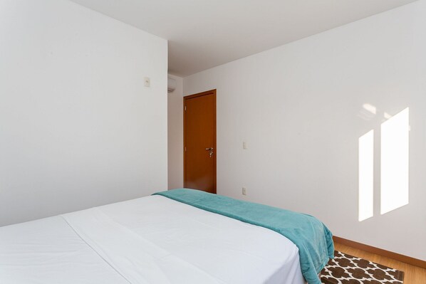 A bedroom with a bed, a wooden door, and a patterned rug.