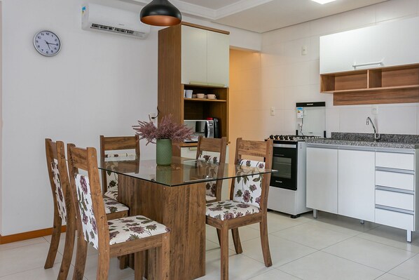 A modern kitchen with white cabinets, a built-in oven, and a coffee machine.