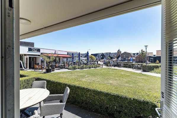 A patio area with outdoor seating, a view of a town with buildings and a church, and a clear sky.