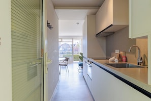 Una cocina estrecha con ventana, un fregadero y un pequeño comedor.