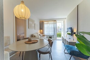A modern living room with a dining table, chairs, a sofa, and a large plant.