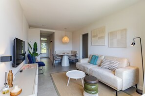 A modern living room with a sofa, a dining table, and a TV.