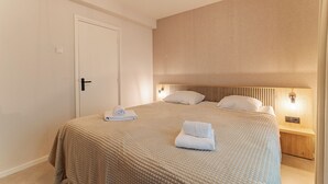 Ein Hotelzimmer mit einem Bett, einer Tür, einem Nachttisch mit Lampe und einer Wandleuchte.