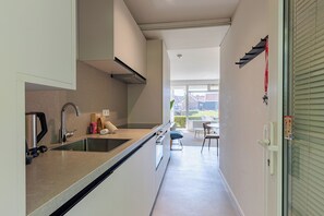A narrow kitchen with a sink, a kettle, and a small countertop.