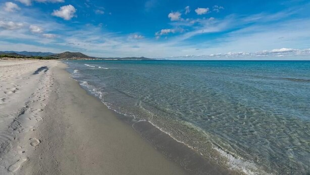 A beach with clear water, a sandy shore, and distant mountains under a blue sky. - Casa Pompia 2 - Two Bedroom Apartment, Sleeps 4 (Siniscola)