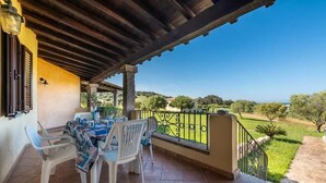 A covered patio with a table and chairs, a view of the countryside, and a railing. - Casa Pompia 2 - Two Bedroom Apartment, Sleeps 4 (Siniscola)